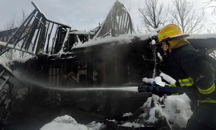 A firefighter sprays water on a snow-covered home still smoldering in the Rock Creek neighborhood of Superior.