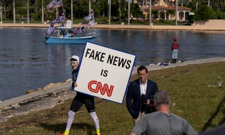 A man walks behind an on-air reporter outside Mar-a-lago, shortly before the former president announced his 2024 run.