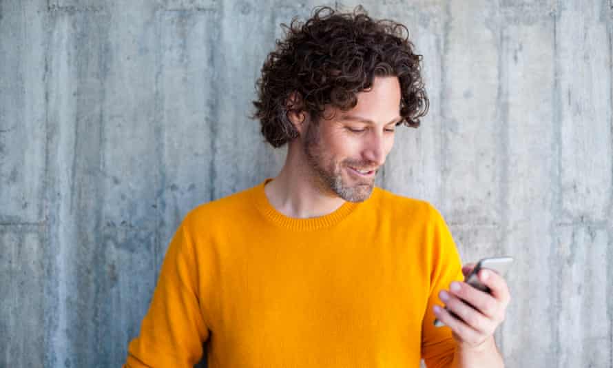 A man smiling as he looks at his smartphone