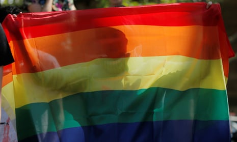 A person is pictured through a rainbow flag