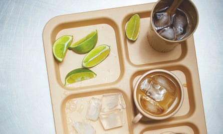 A compartmentalised tray with plastic beakers of dark drink, slices of lime and ice cubes
