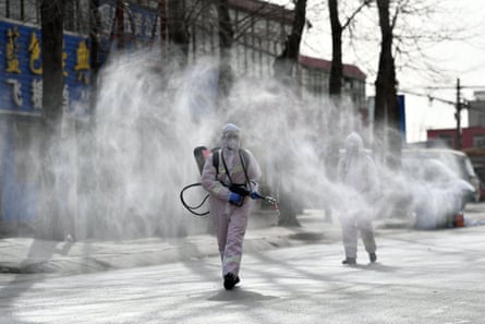People in protective suits spray disinfectant on a street in northern China’s Hebei province on 15 January 2021.