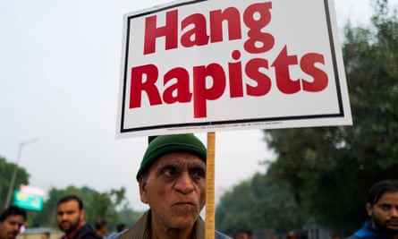 A protester holds a placard calling for rapists to be hanged