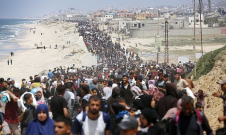 Hundreds of people crowded together walking along a beach-front road