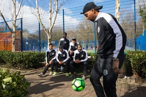 Adrian Clifton juggles a football as his teammates look on.