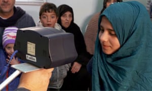 a syrian girl having her iris scanned at a refugee camp in jordan