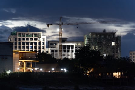 A group of office blocks lit up at night with a construction crane behind them