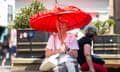 A woman with a red unbrella takes shelter from the sun as people in the city of York, North Yorkshire endure the hottest day on record as the temperature in the UK passes 40 degrees Farenheit on July 19th 2022 as the UK continues to endure the heatwave and a period of extreme weather conditions.
