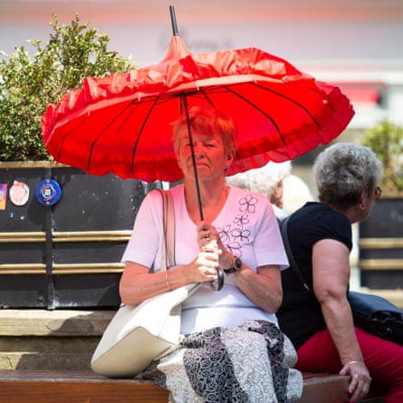 A woman with a red umbrella takes shelter from the sun in York.