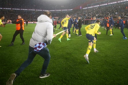 Trabzonspor fans invade the pitch and chase off Fenerbahce players.