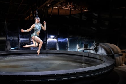 A dancer suspended over water by her hair.