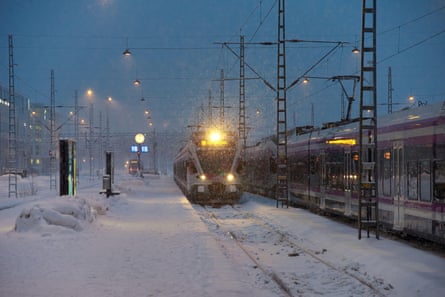 A commuter train arrives at Helsinki central railway station in a heavy snow storm at dawn