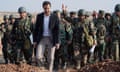 Bashar al-Assad, in smart jacket and trousers, leads a group of soldiers in helmets and camouflage