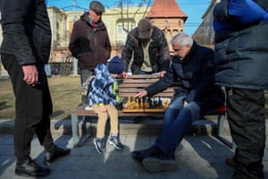 A man plays chess with a young boy on a bench on the central promenade in the western Ukrainian city of Lviv