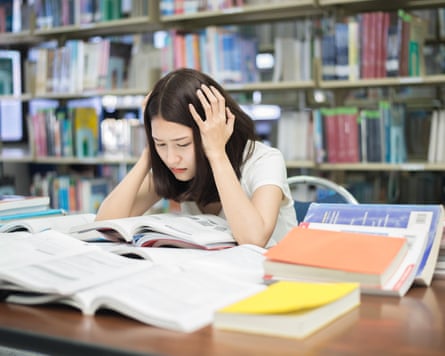 a stressed student pores over books in a college library