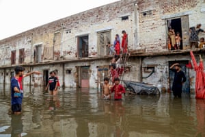 People stand in floodwaters and on the ledges of buildings after homes were submerged by flooding in Hyderabad, Pakistan
