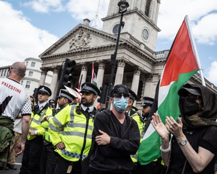 Protesters wearing face masks in Trafalgar Square, alongside police