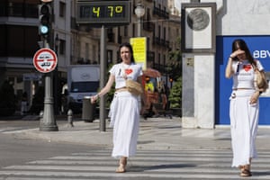 Two people in matching white ‘I heart Granada’ T-shirts and white dress walk across a pedestrian crossing