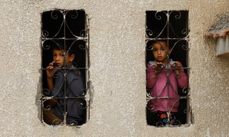 Palestinian children look out from a window with a grill at the site of Israeli strikes on houses in the southern Gaza Strip.