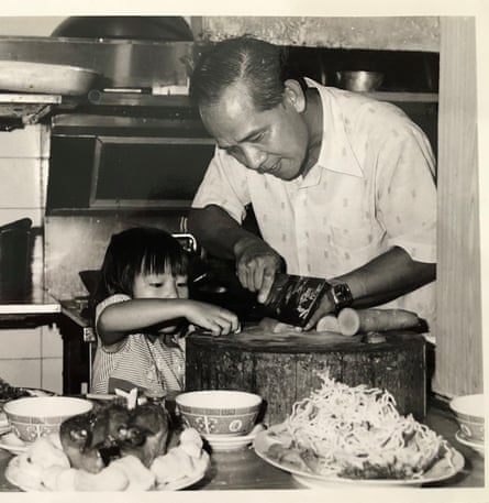 A black and white photograph of a young child with her father in a restaurant kitchen.