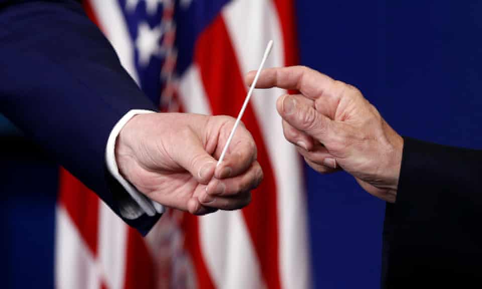 Donald Trump, left, hands a swab that could be used in coronavirus testing to Mike Pence during a taskforce briefing in Washington DC, on 19 April. 