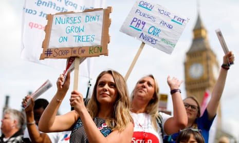 Demonstrators hold placards at a protest, organised by nurses, against the government’s pay cap on public sector workers.