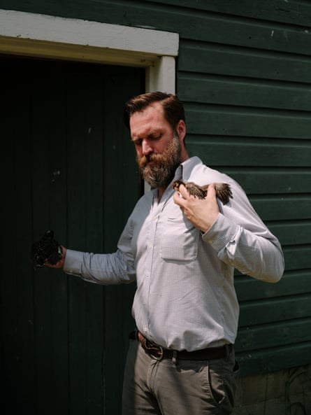 Man holding chicks outside a house.