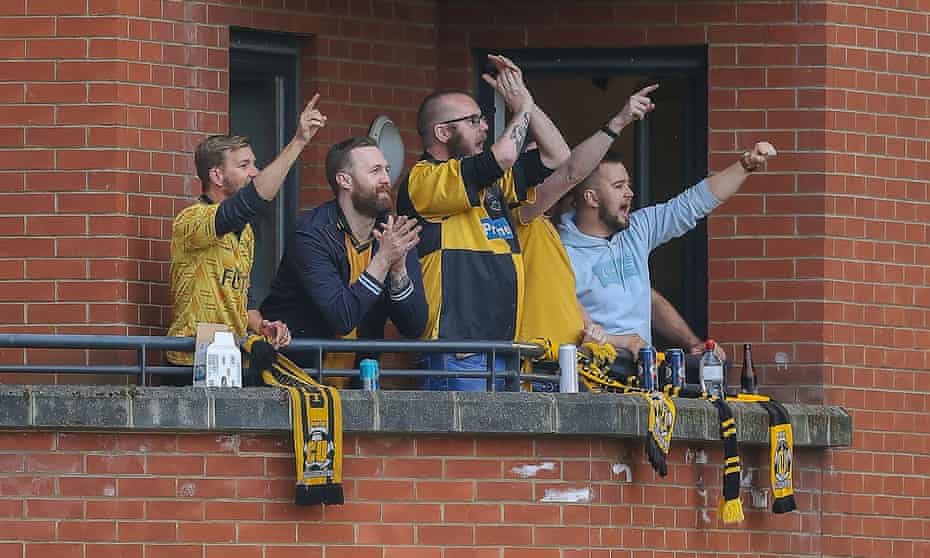 Cambridge fans watch their team win at Leyton Orient last month from the balcony of one of the flats in the corner of the ground. They’ve not won since.