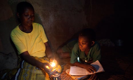 A mother lights a small lamp for her child to study by in Masaka, Uganda, East Africa