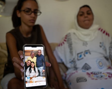Fakir’s sister Khadija with his niece Yossra, showing a photo on a phone of him with family members
