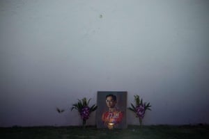 A lit candle and flowers adorn an image of the late Thai king Bhumibol Adulyadej on the outer wall of the Grand Palace at dawn