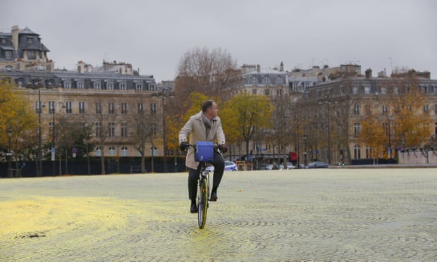 A man rides his bicycle on yellow paint poured on the street during a protest by activists from environmental group Greenpeace on the Champs-Elysee in Paris, ON Friday.