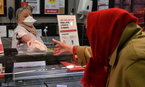 A woman in a mask serves a supermarket customer