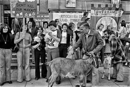 Black and white photo of a protest at Mudchute City Farm, London, September 1977, with people holding banners, and a goat at the front
