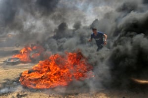 A Palestinian man uses the smoke from burning tyres for cover near Khan Yunis