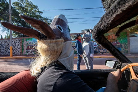 Flores and a costumed mascot talk while Daniel, a sanctuary worker, drives by wearing a donkey mask