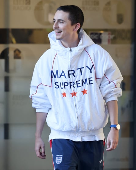 Timothée Chalamet wearing a white windbreaker with ‘Marty Supreme’ printed on the front and three red stars