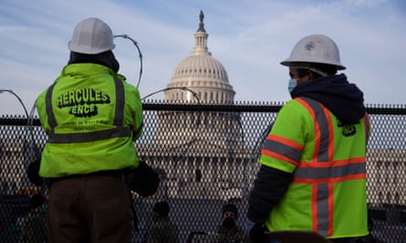 Workers install razor wire atop fencing outside the US Capitol ahead of Biden’s inauguration.