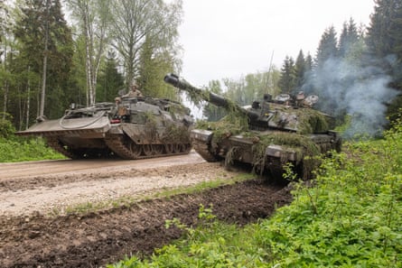 Soldiers on tanks on a dirt road next to a forest