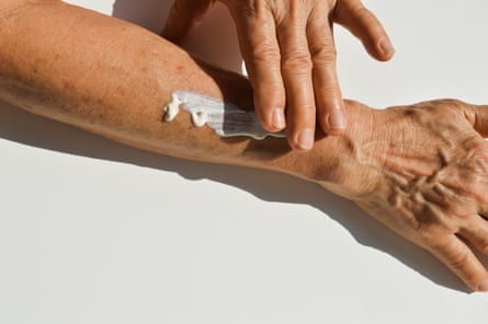 A person applying sunscreen to their arm
