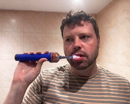 Writer Alan Martin using the Dyson CameraJet toothbrush in a bathroom.