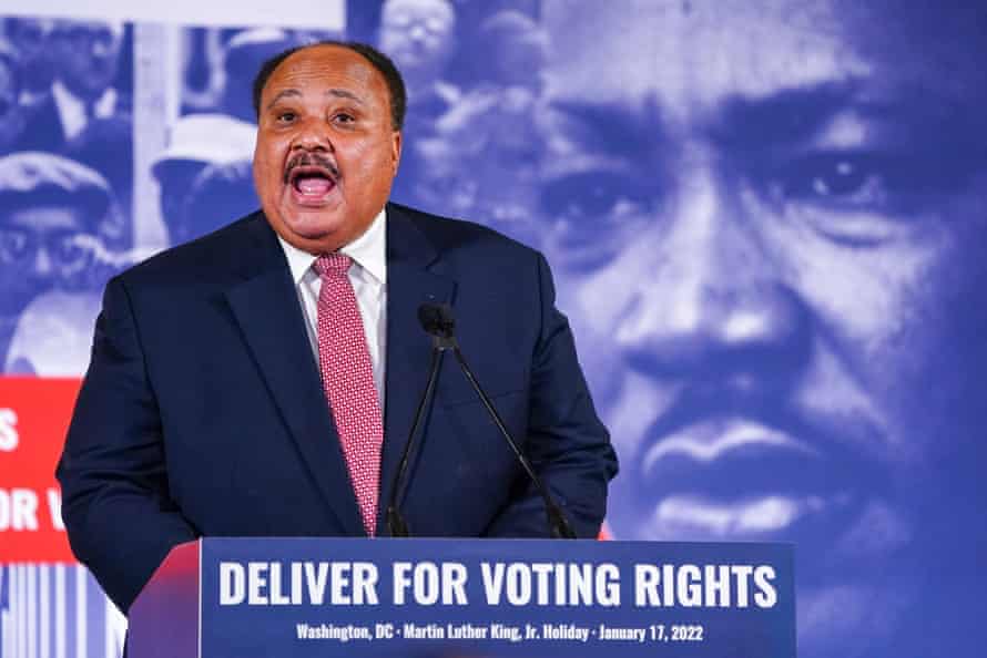 A man stands behind a podium with a large image of Martin Luther King Jr. in the background.