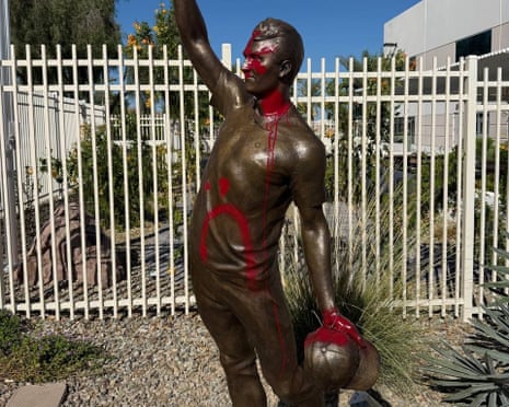 statue of man holding hat and waving splattered with red paint