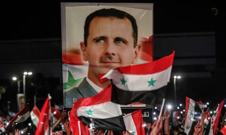 Syrians wave national flags and carry a large portrait of Bashar al-Assad after elections in May