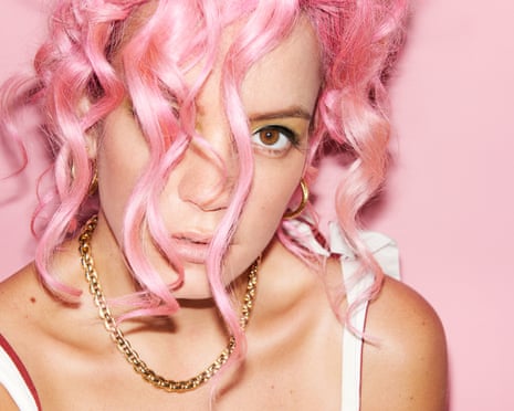 Head shot of Lily Allen with pink hair, against pink background