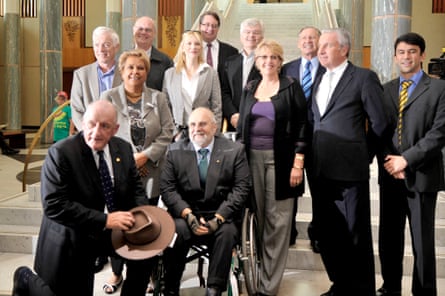 Roger Beale seated in a wheelchair with 10 other men and women who are standing in 2008 as part of the 2020 summit