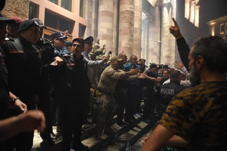 Protesters line up in opposition to police on the steps of a large building