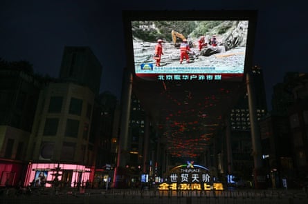 A screen outside a shopping mall in Beijing shows a news report featuring rescue workers at in Gyirong County, in China’s western Tibet region near the border with Nepal on August 27, 2026. More than 1,300 people were reported missing and more than 350 were confirmed dead after flash floods and landslides at the Nepal-Tibet border.