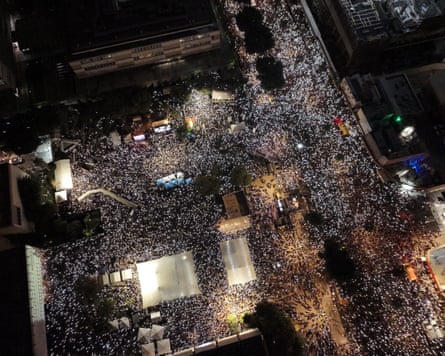 Crowds fill a square at night as seen from above