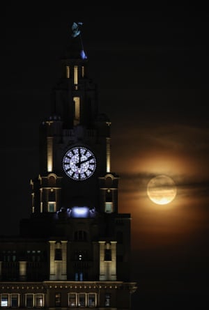 The full moon rises behind the Royal Liver Building in Liverpool, United Kingdom.